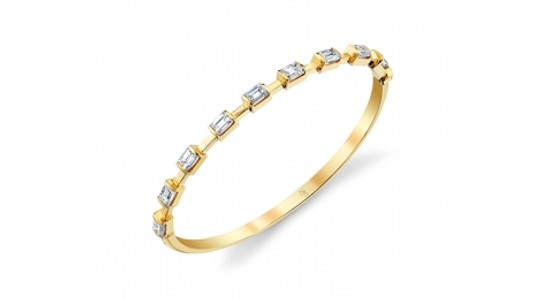 a yellow gold bangle featuring emerald cut diamonds