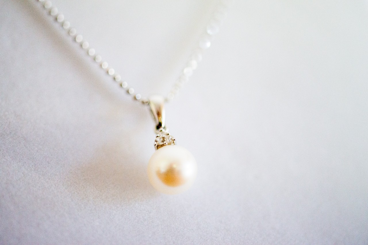 a white gold pendant necklace featuring a single pearl on a white surface