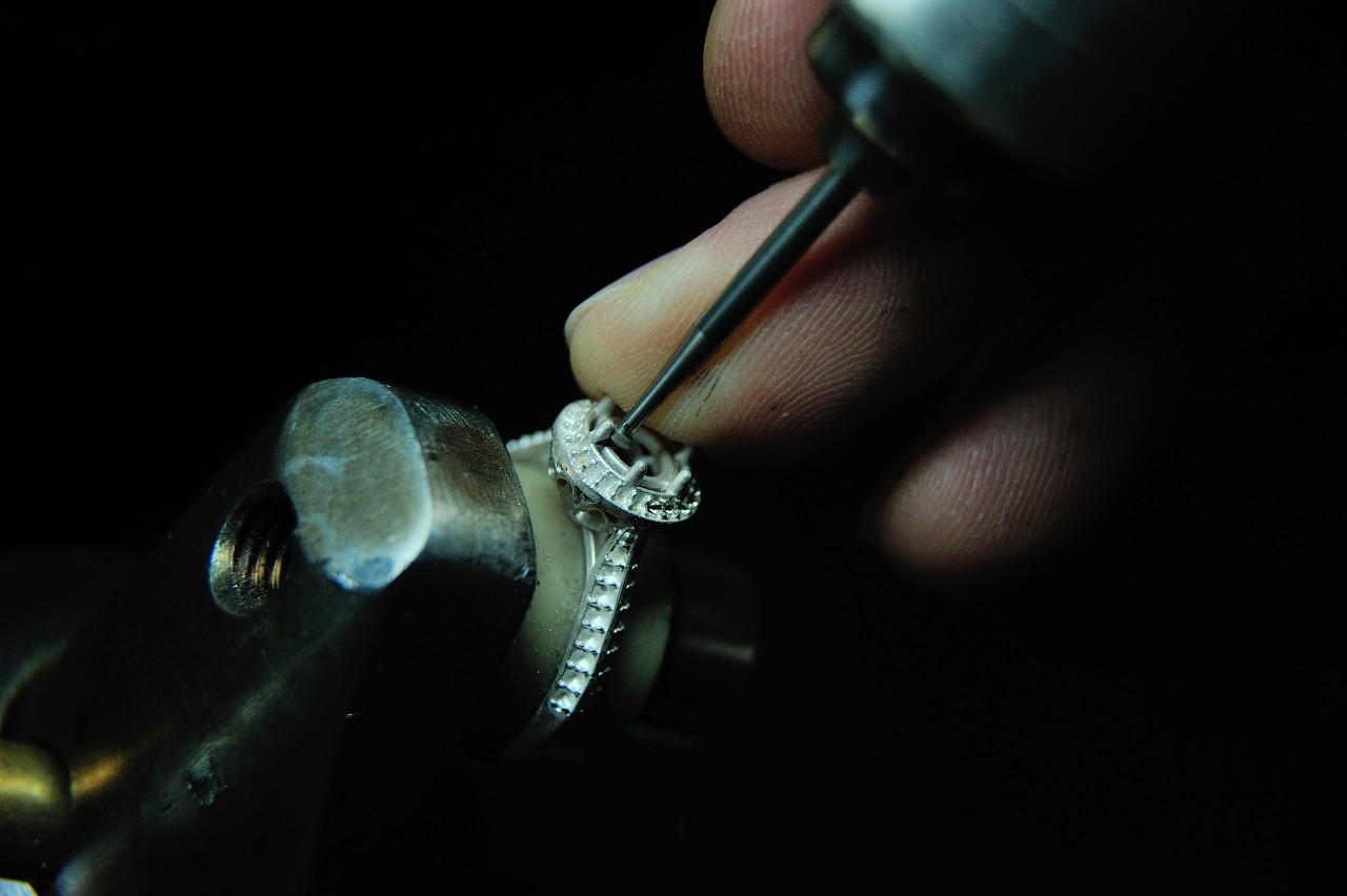 A close-up of a jeweler working on a white gold engagement ring setting.
