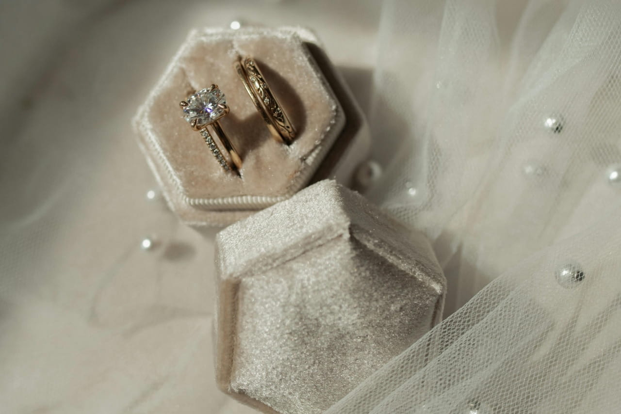 A matching yellow gold wedding ring set inside a beige jewelry box.