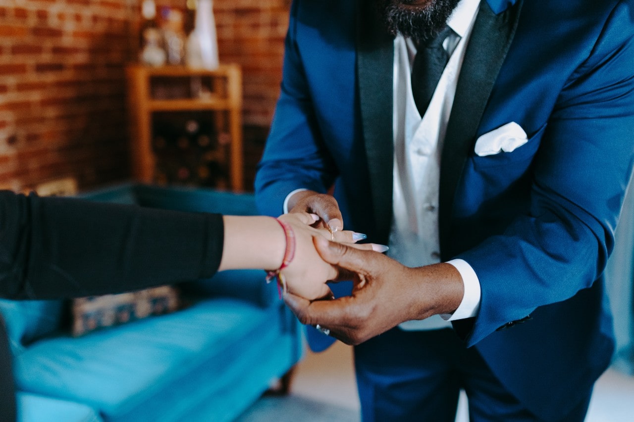 A close-up of a jeweler inspecting a ring on a client&rsquo;s finger.