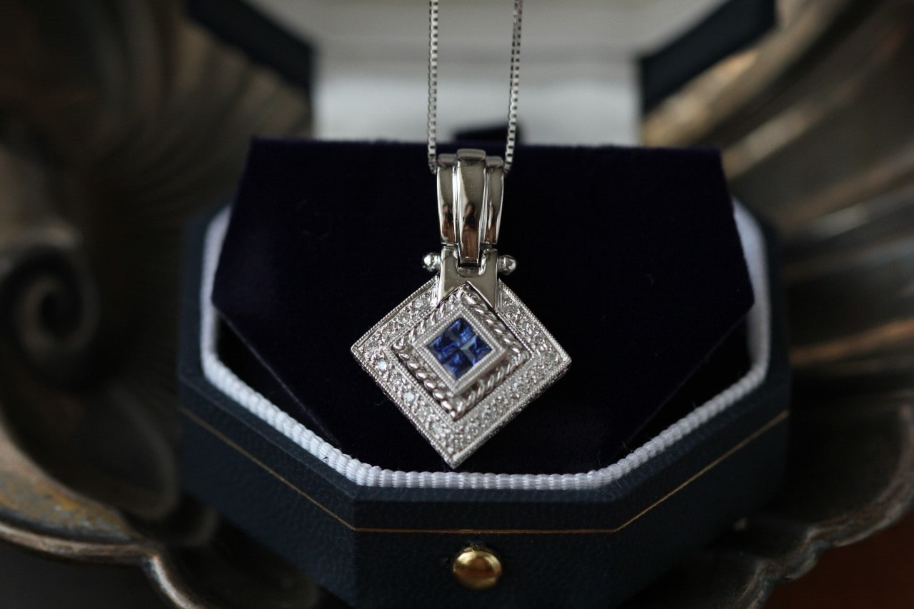 a gleaming white gold necklace with a blue gemstone