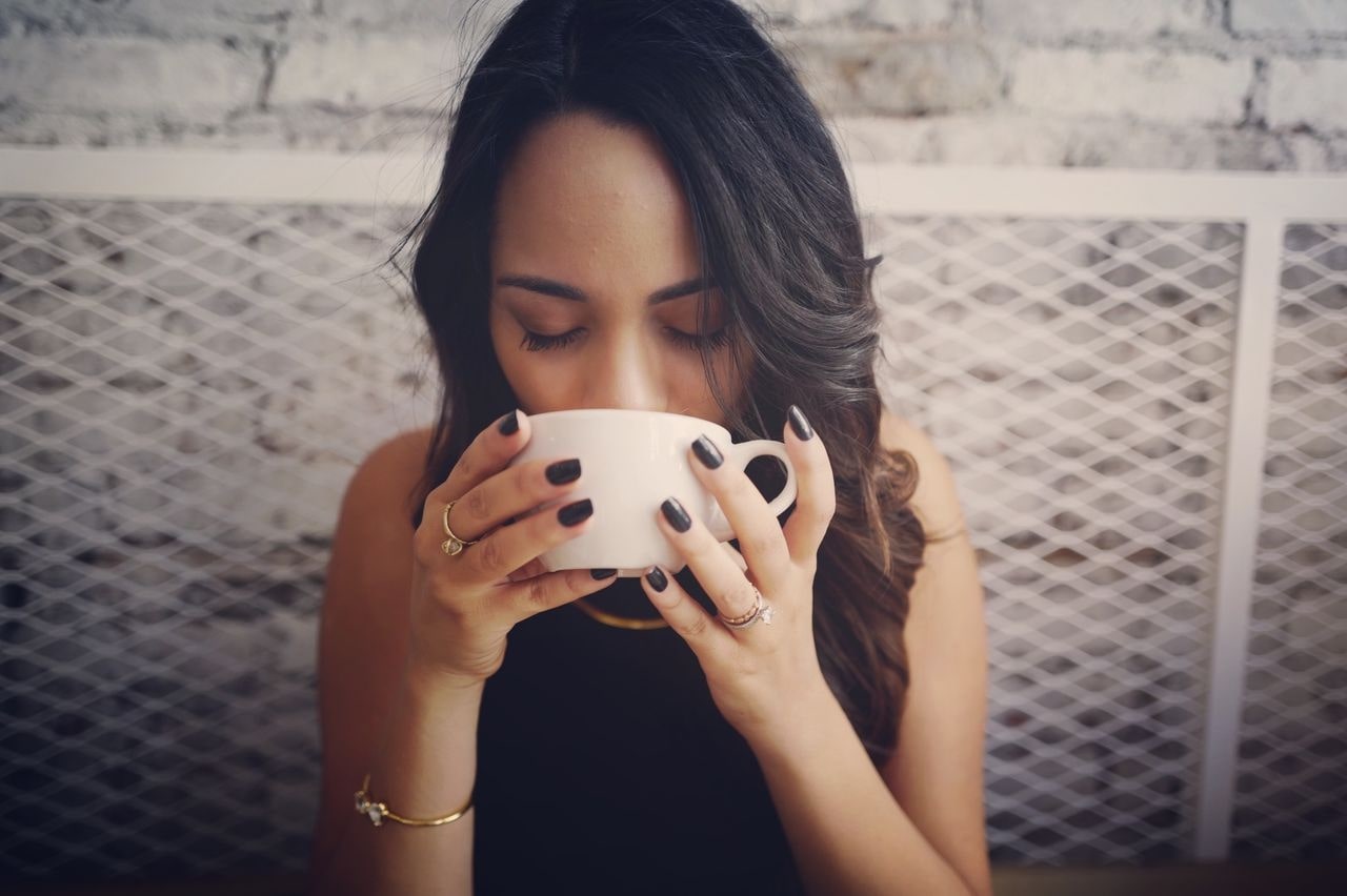 lady holding a coffee mug and wearing fashion rings