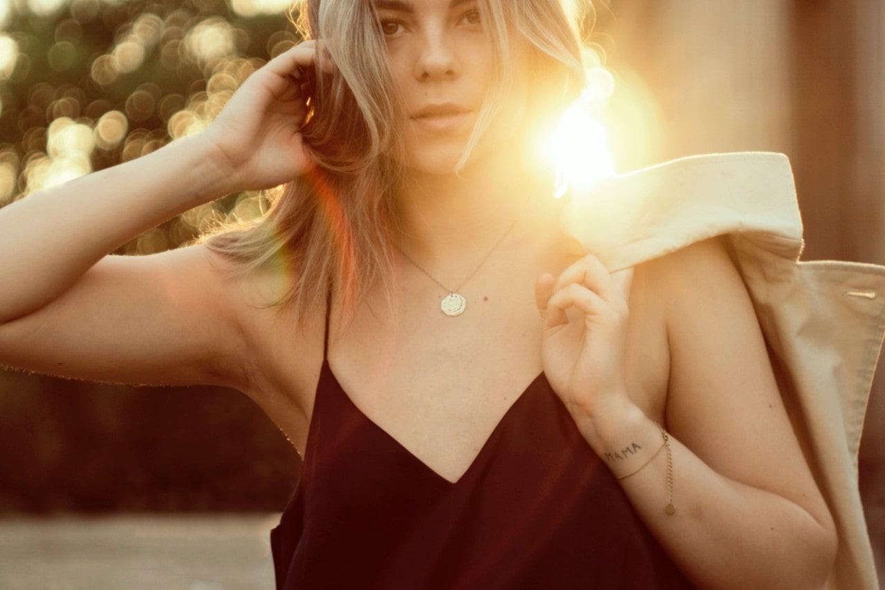 a woman wearing a yellow gold circle necklace and holding her jacket over her shoulder