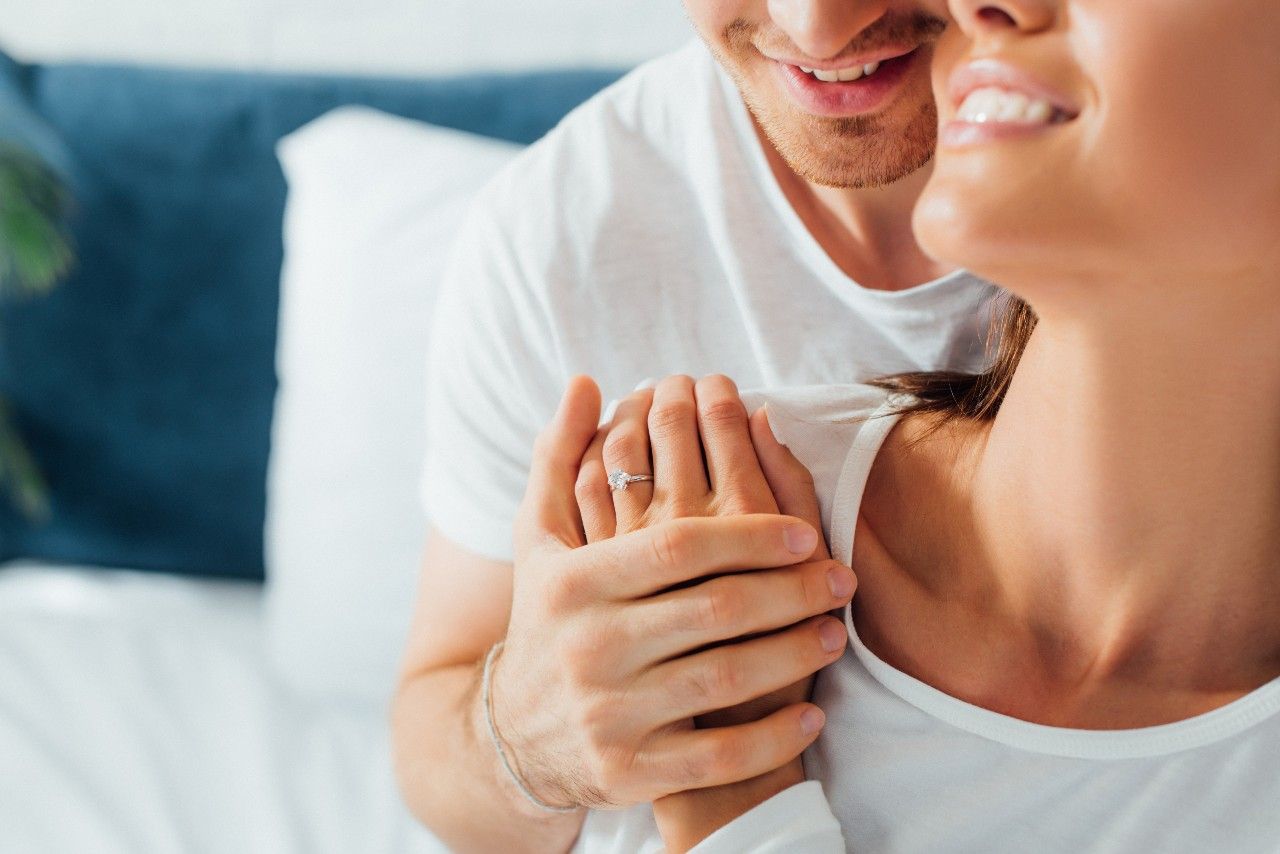 lady holding a man’s hand and wearing a white gold engagement ring