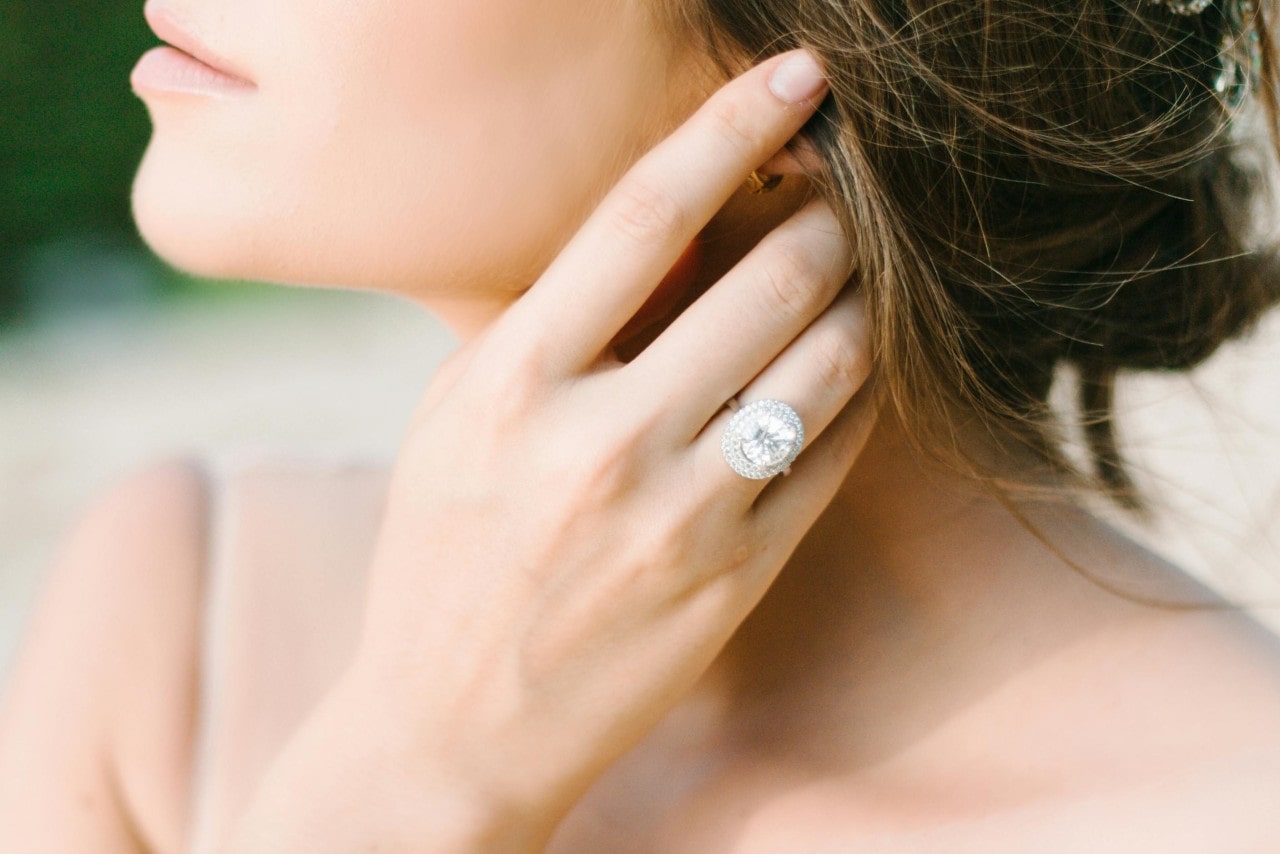 A close-up of a bride-to-be wearing an elegant halo engagement ring.