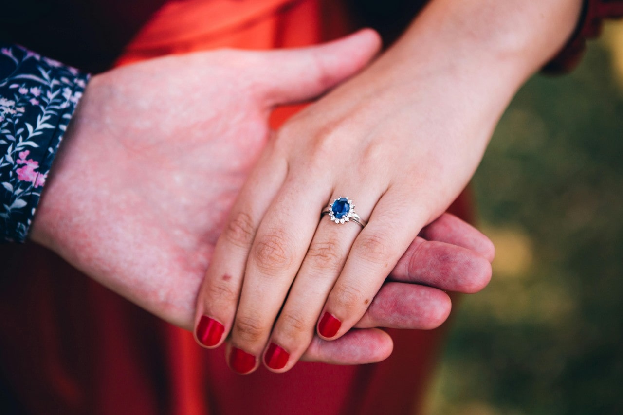 A sapphire center stone ring with a diamond halo around the deep blue gemstone.