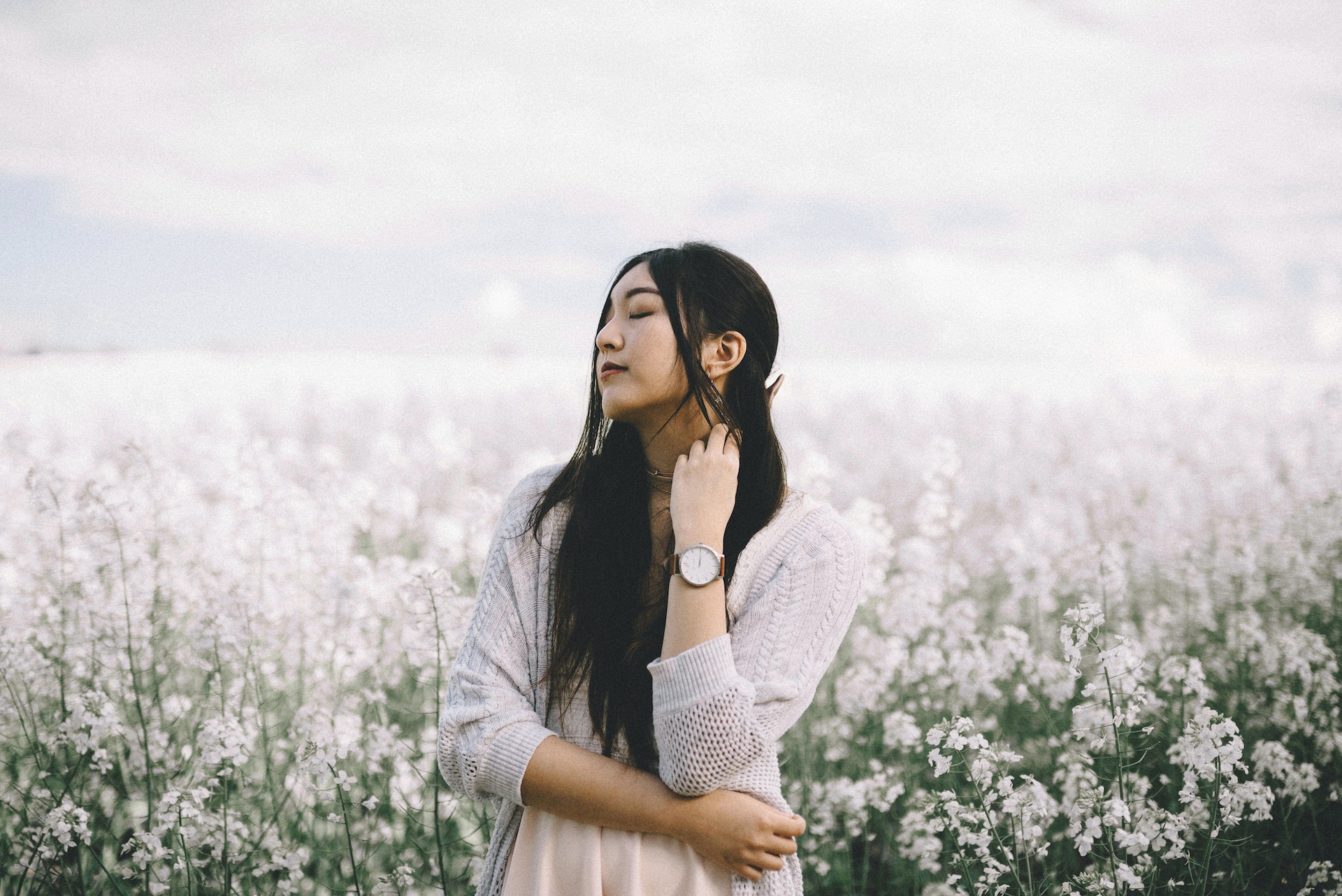 lady wearing a luxury watch and standing in a field of flowers