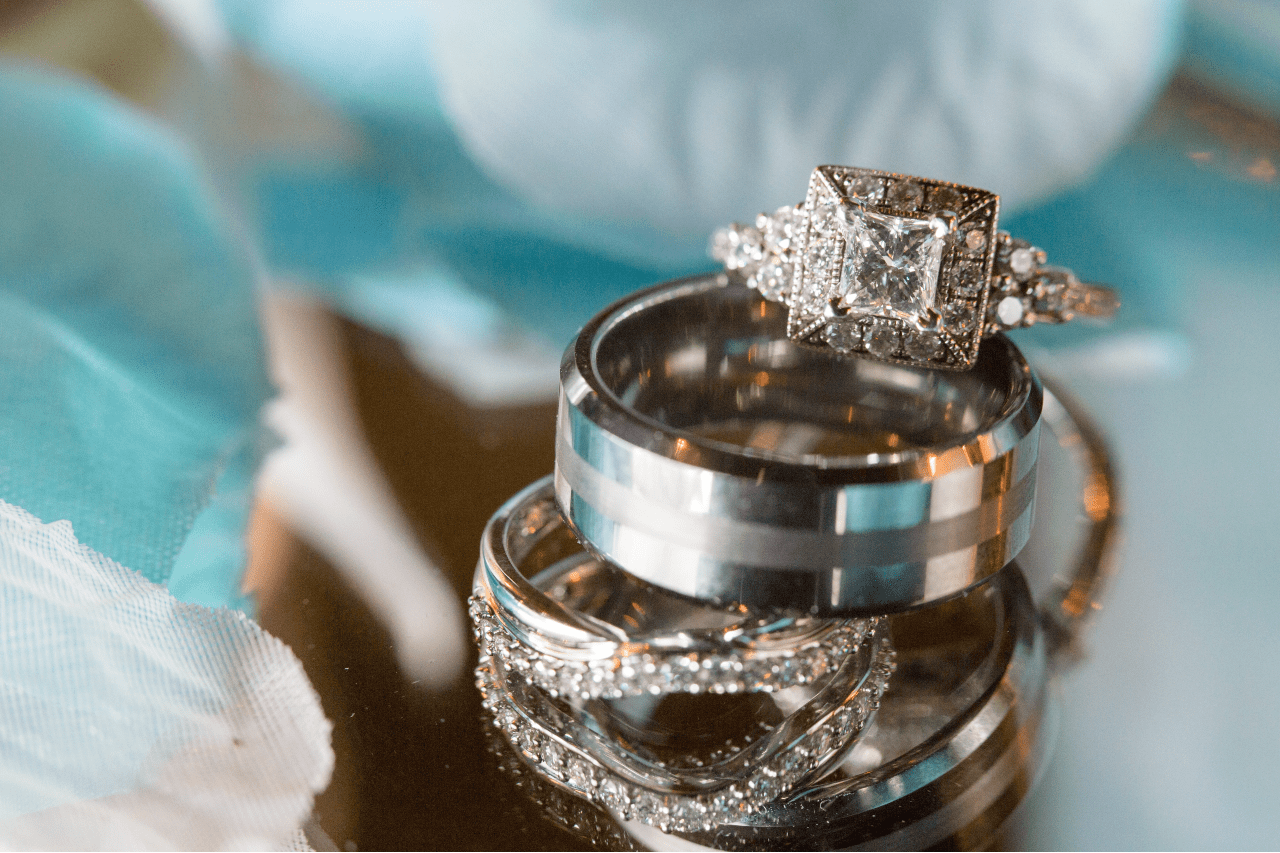 Engagement ring with a halo and pave setting surrounding the center stone, sitting on several wedding bands