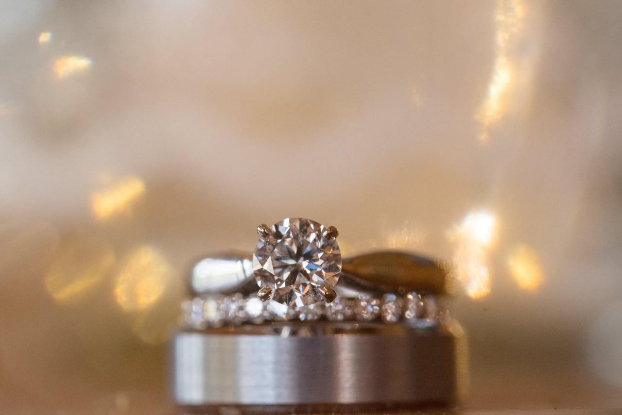 Engagement ring with round center stone sitting on several wedding bands