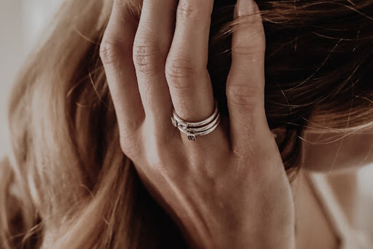 A woman runs her fingers through her hair while wearing Armenta fashion rings