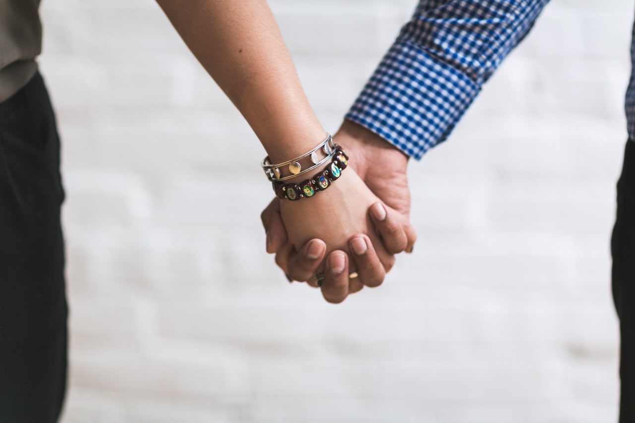A woman wearing two Armenta bangles holds hands with her lover