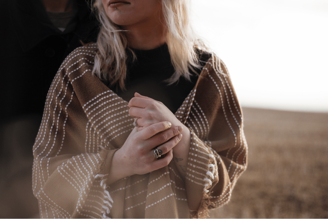 A woman standing in a field with a poncho wears fashion rings from Armenta