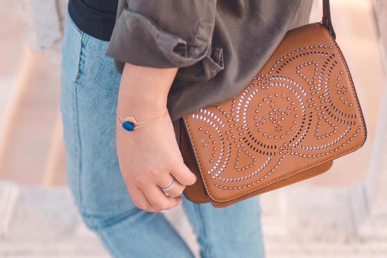 A woman walking and wearing a rose gold bracelet with a sapphire charm on it