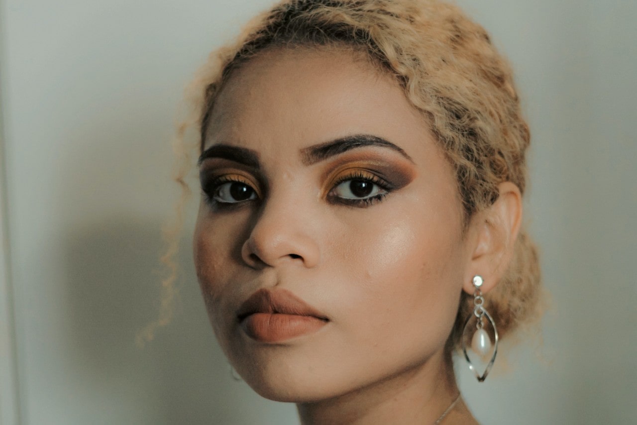 A woman wearing makeup and pearl earrings in her home.