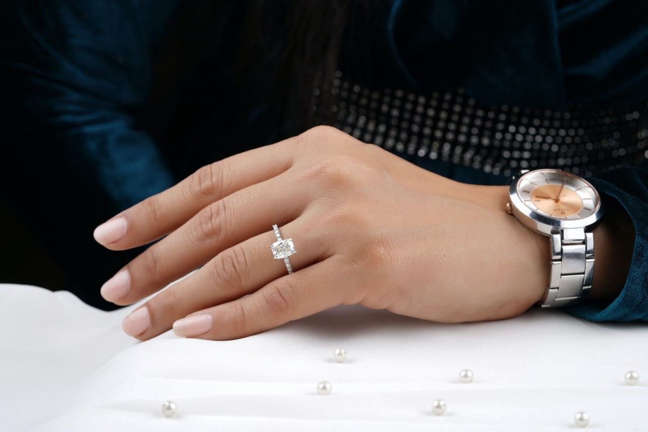 A close up of a woman’s hand with stainless steel wristwatch and white gold emerald cut side stone ring. A close up of a woman’s hand with stainless steel wristwatch and white gold emerald cut side stone ring.