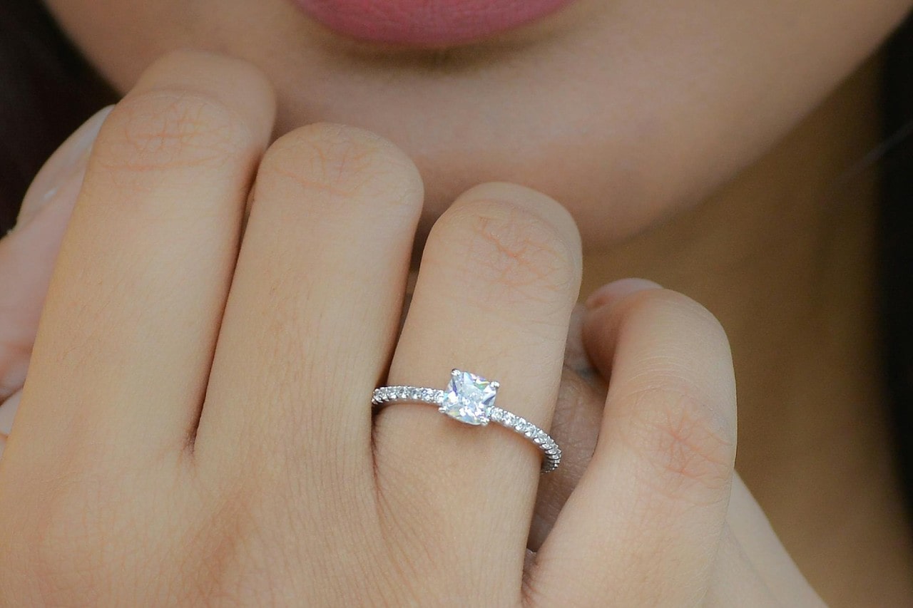 A close up of a white gold diamond side stone engagement ring on a woman’s finger. A close up of a white gold diamond side stone engagement ring on a woman’s finger.