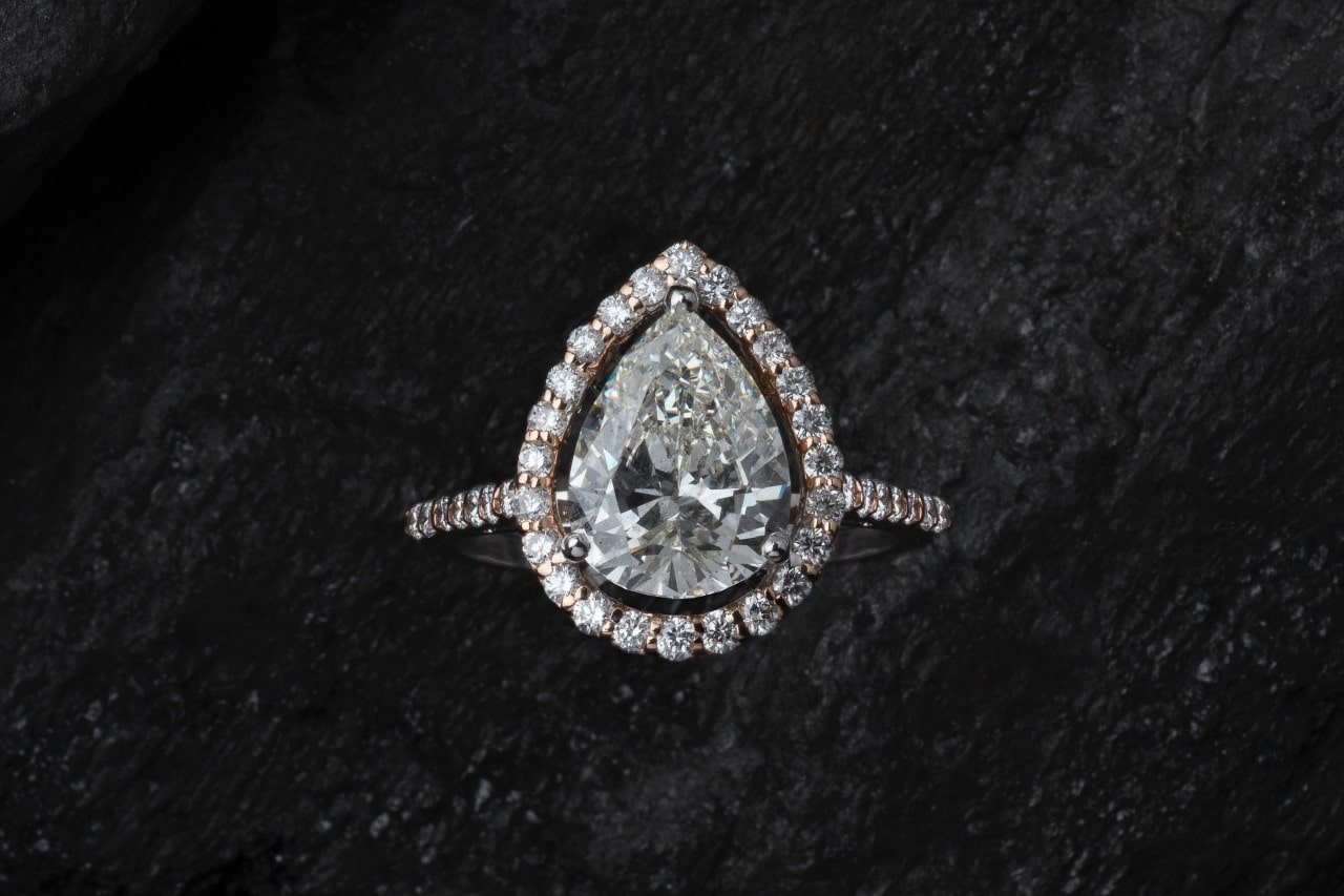 Pear shaped diamond engagement ring on a black background