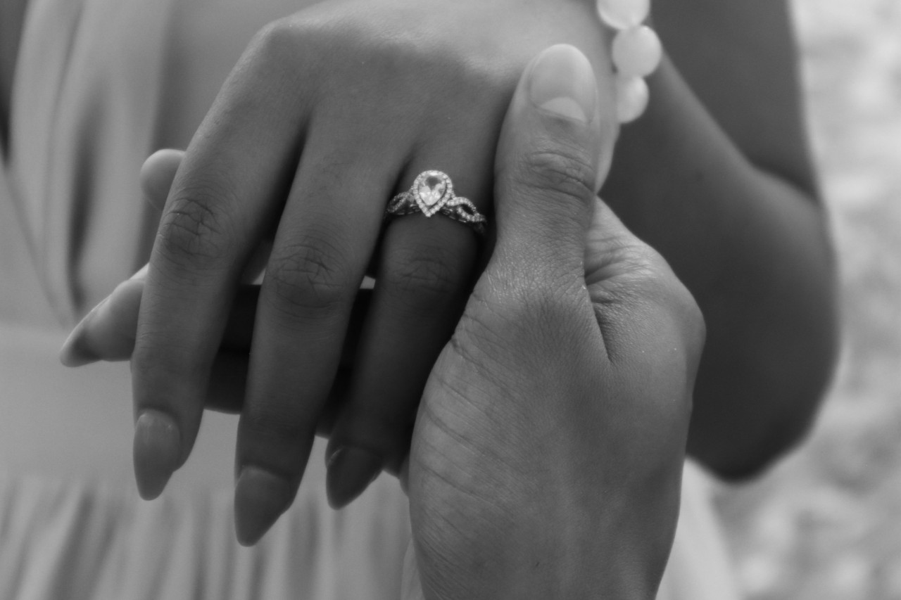 Black and white photo of a lady’s hand wearing a pear shape diamond ring
