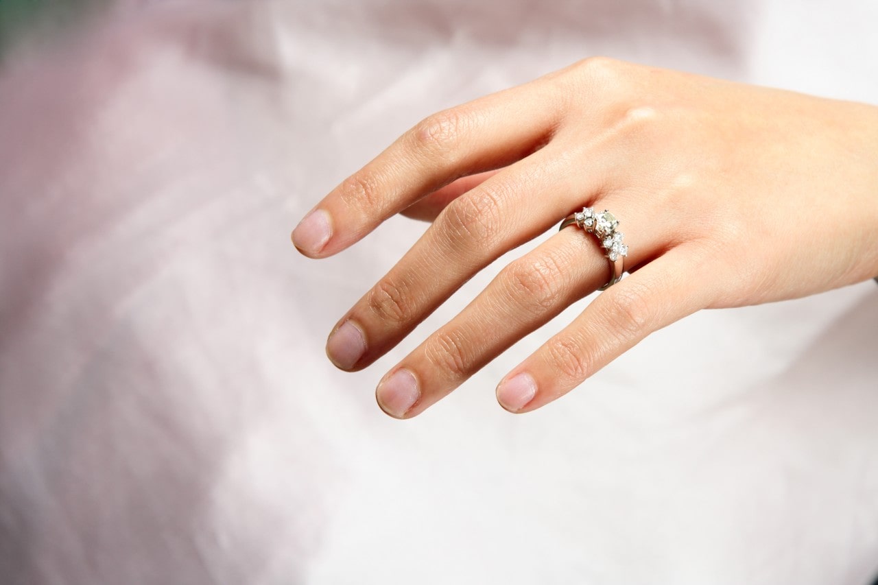 A bride with her side stone engagement ring that features clusters of small diamonds on the sides of the center stone