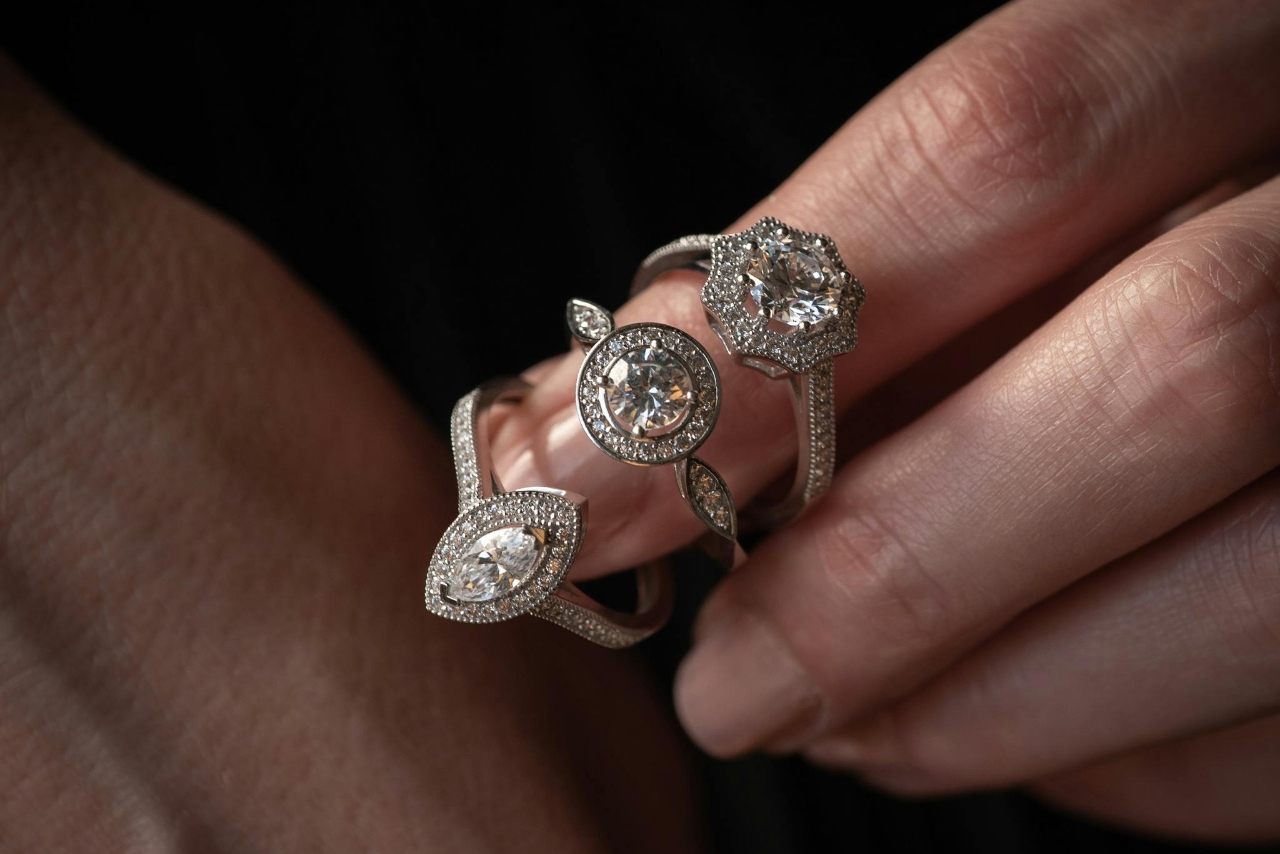 A woman with three different diamond cut engagement rings around her pointer finger.