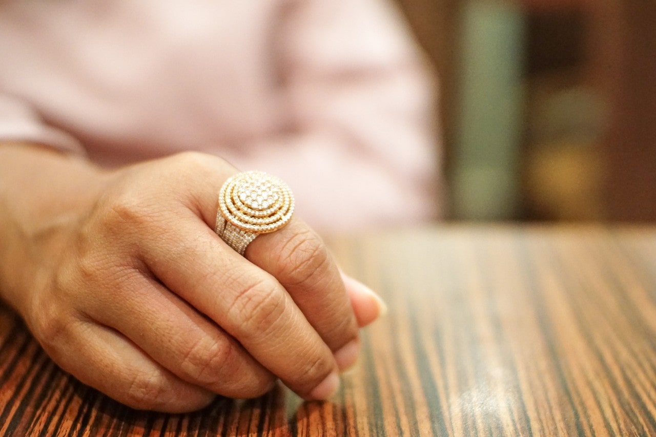 Woman rests her hand on a wooden table while sporting a Sylvie fashion ring
