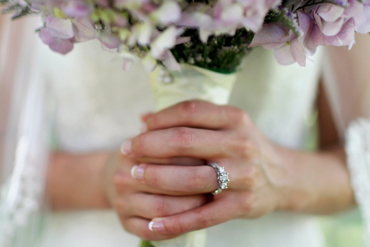 Bride holding her bouquet and wearing a silver three stone engagement ring