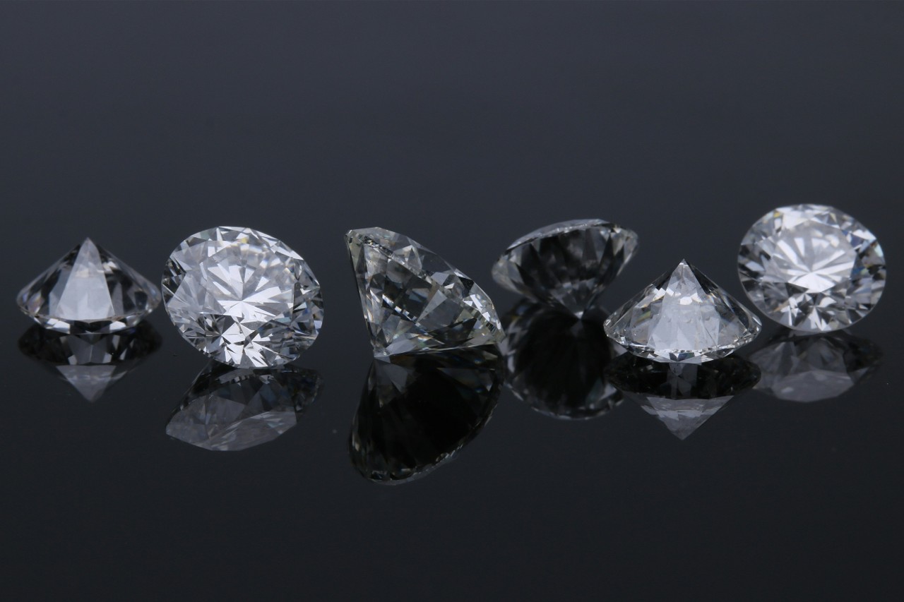 six round cut diamonds in a line on a dark reflective surface six round cut diamonds in a line on a dark reflective surface