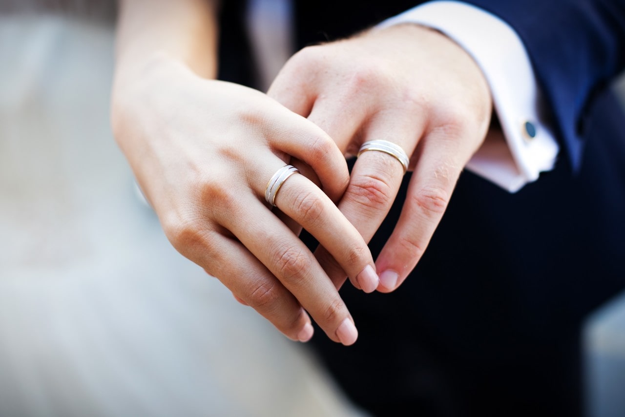 a bride and groom’s hand wearing matching wedding bands