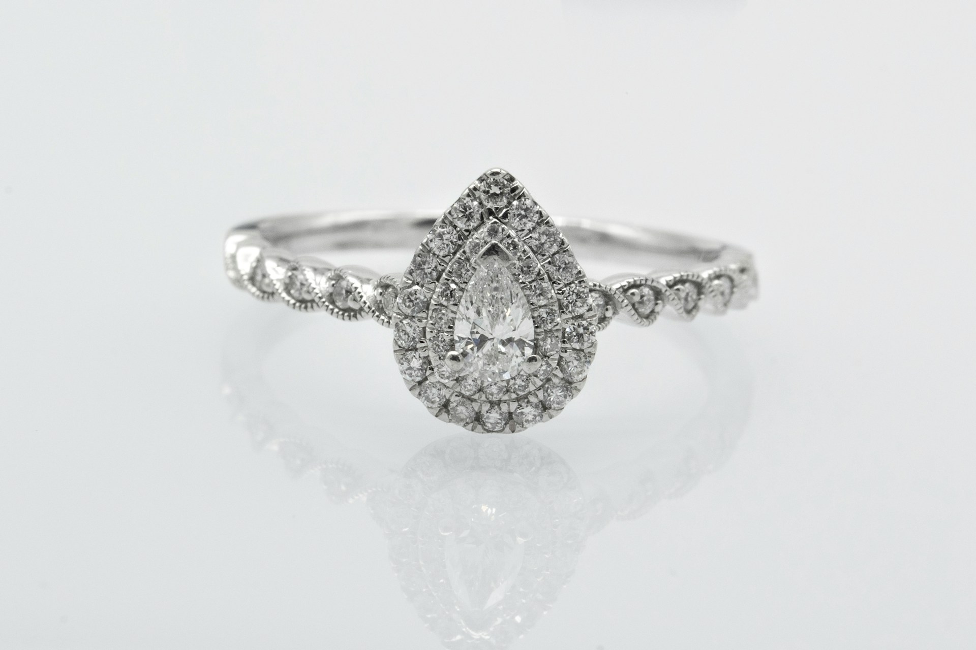 a pear shape halo engagement ring on a gray background